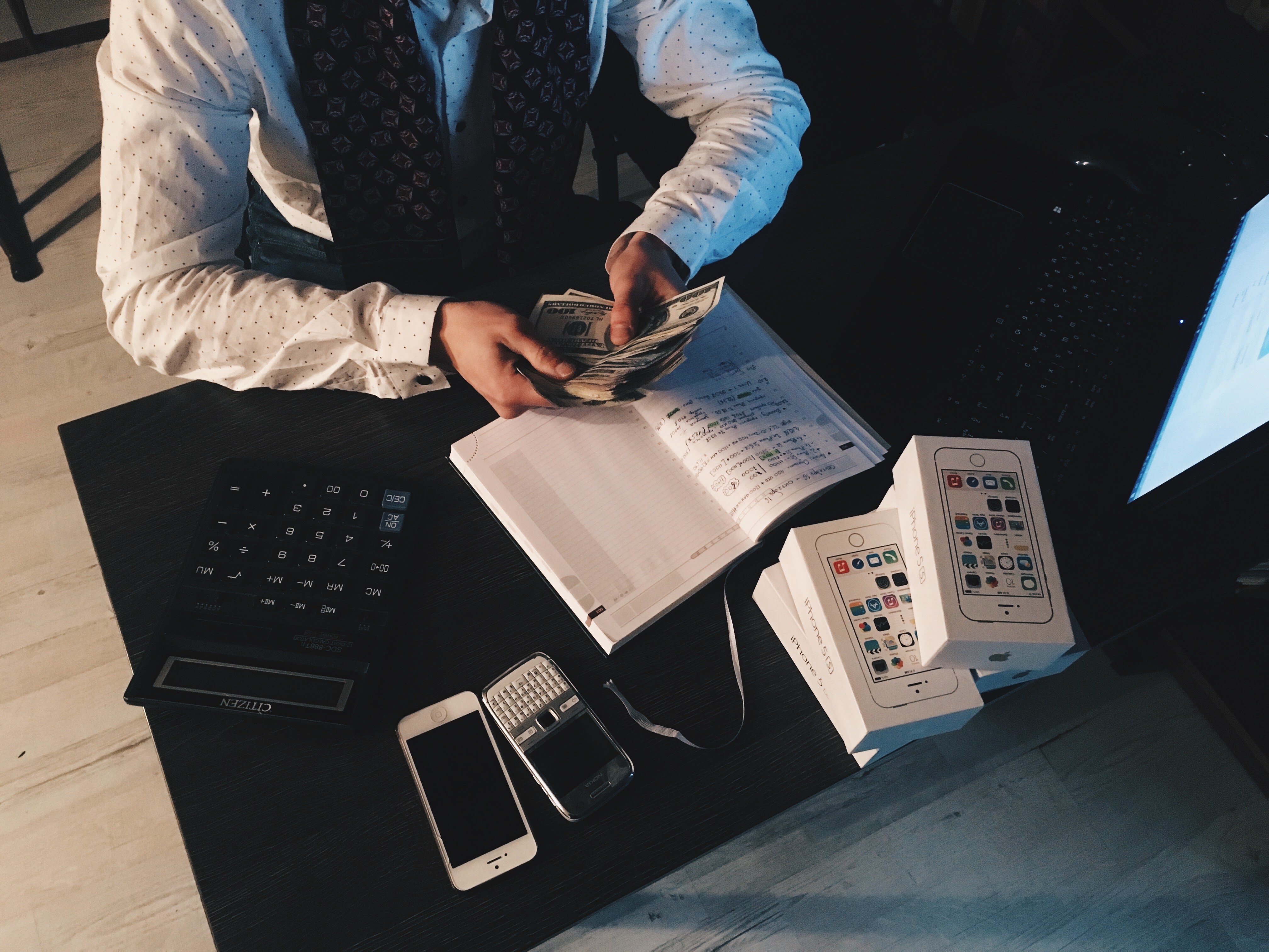 Man sitting at a desk next to a calculator counting money