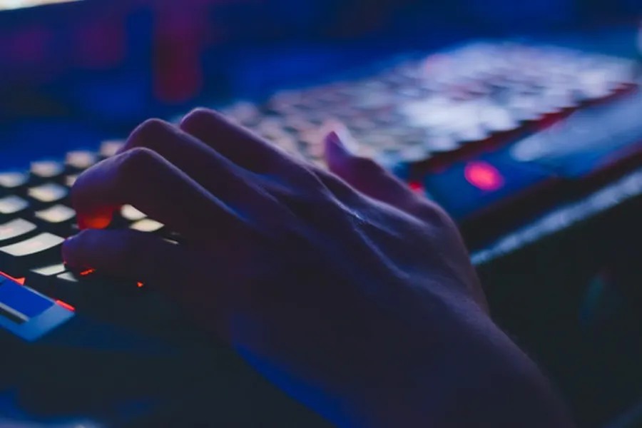 Man's hand typing on a keyboard in the dark to symbolise anti-hacking compliance training