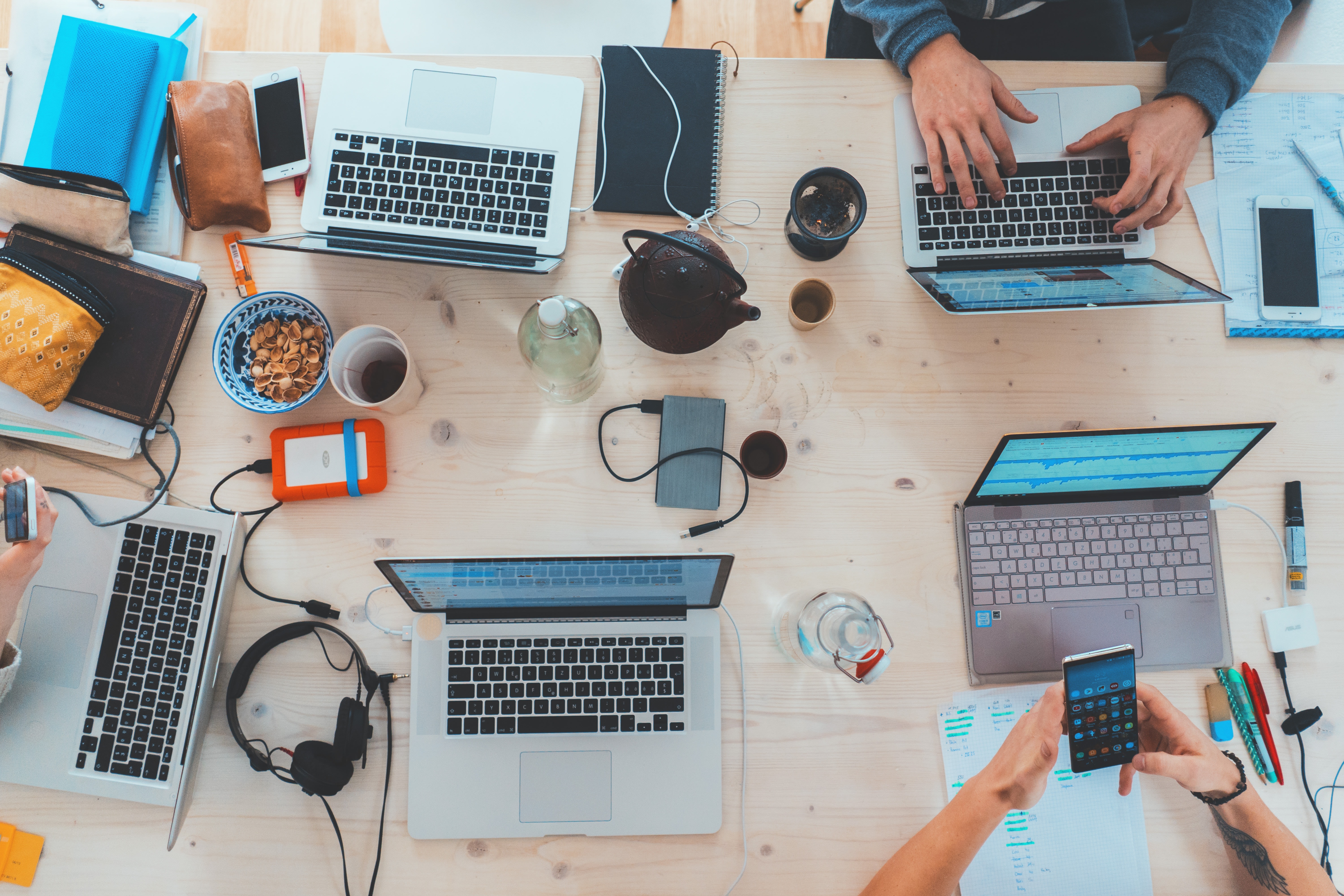 Group of people working onl laptops with coffee and headphones on the table