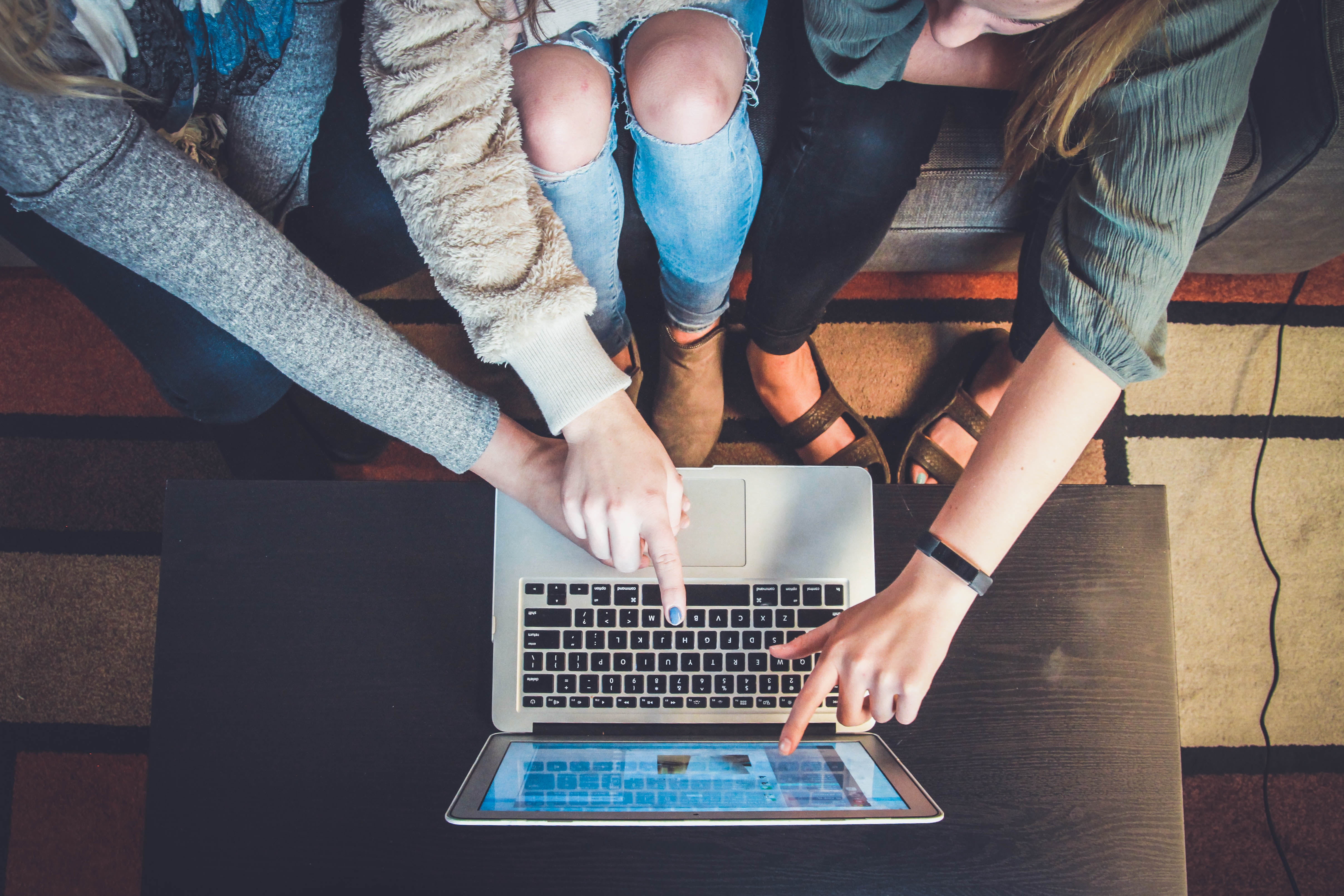 Several women pointing at a laptop screen