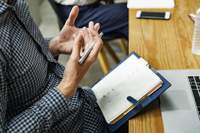 Man staring at his hands while writing in a notebook