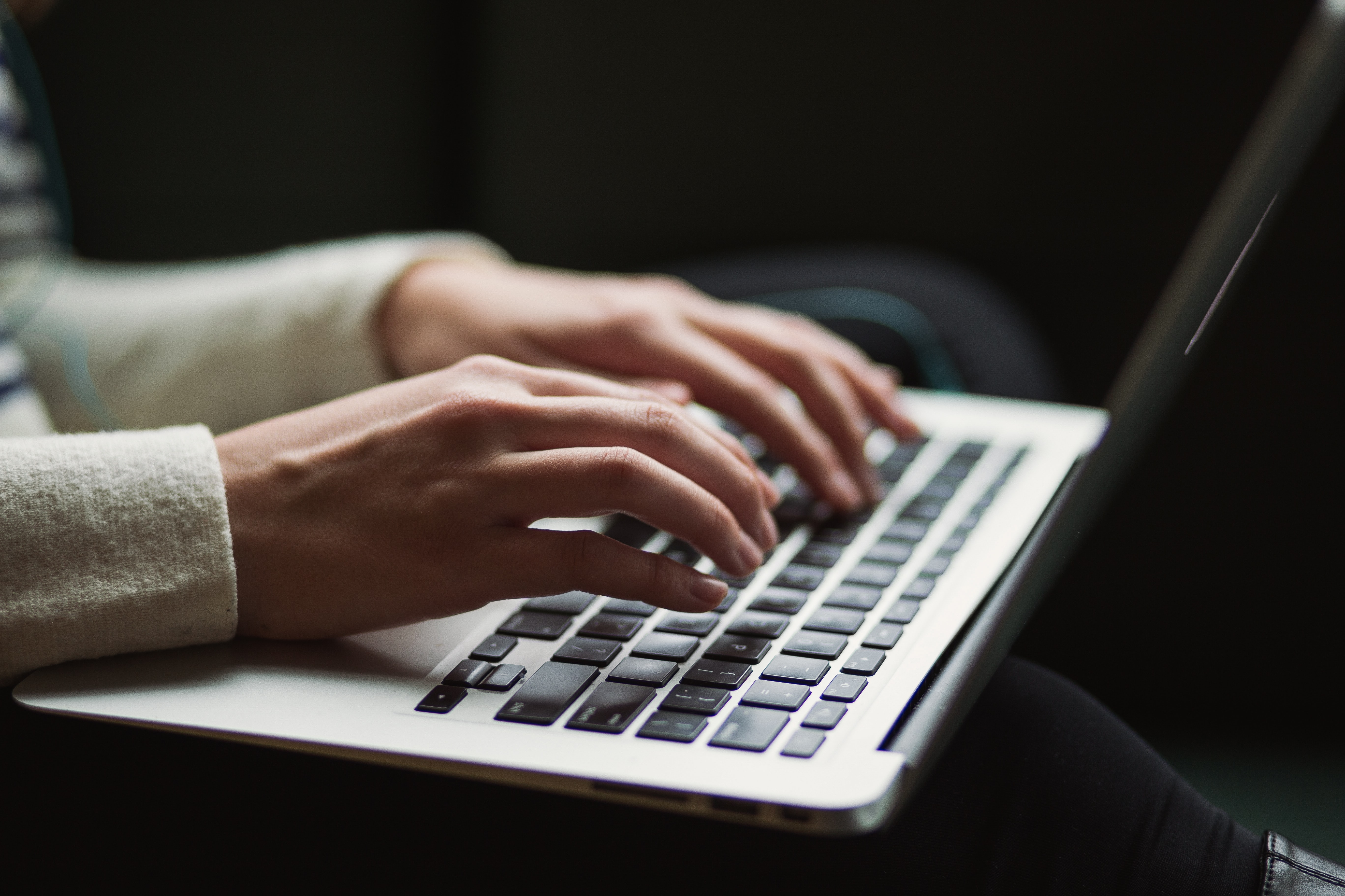 Disembodied hands typing on a laptop in a dark room