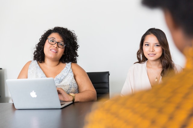 Two women talking in a meeting room to symbolise a common workplace challenge